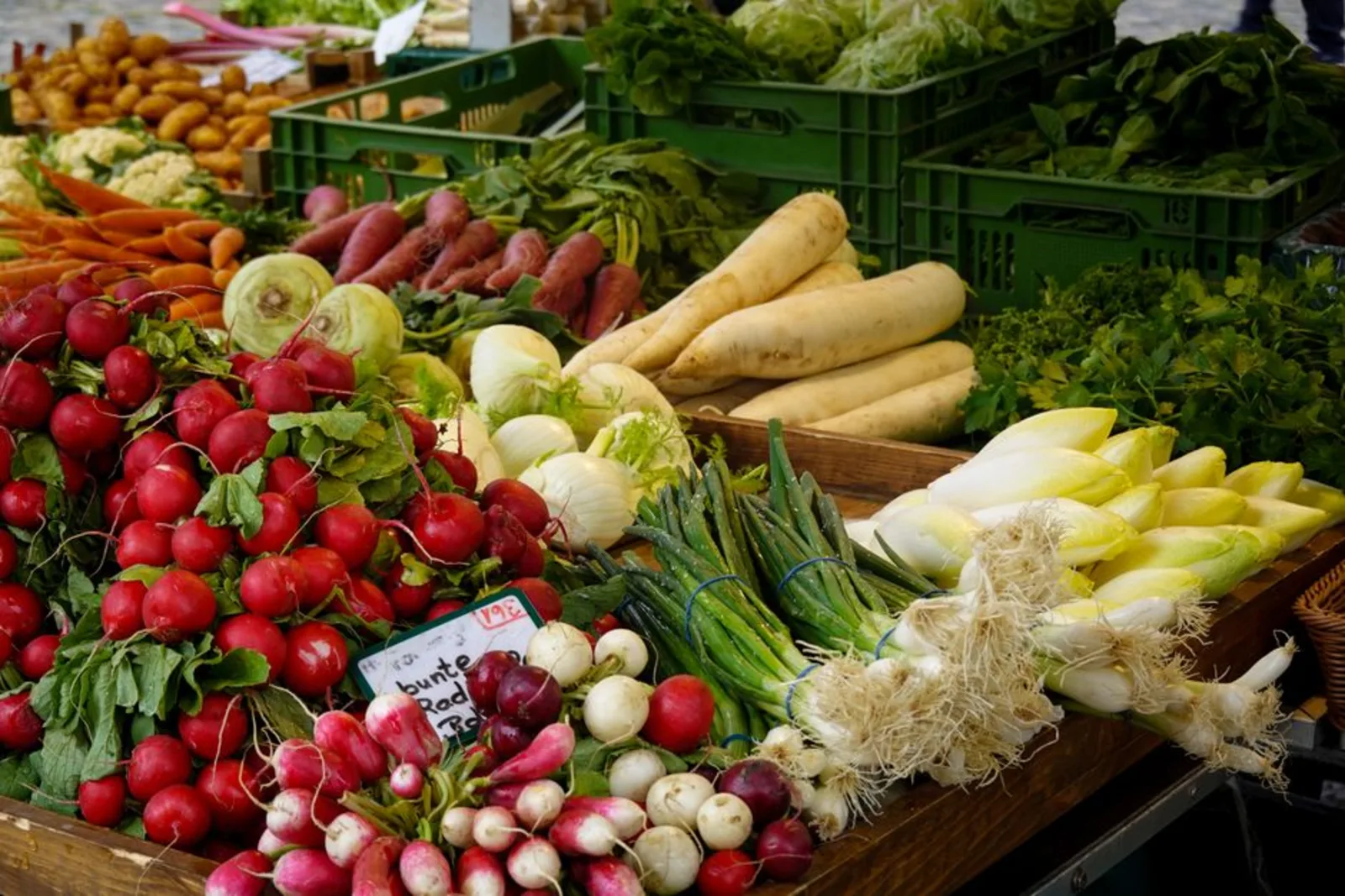 Fresh radishes, greens, and root vegetables on a Boulder Farmers Market produce stall