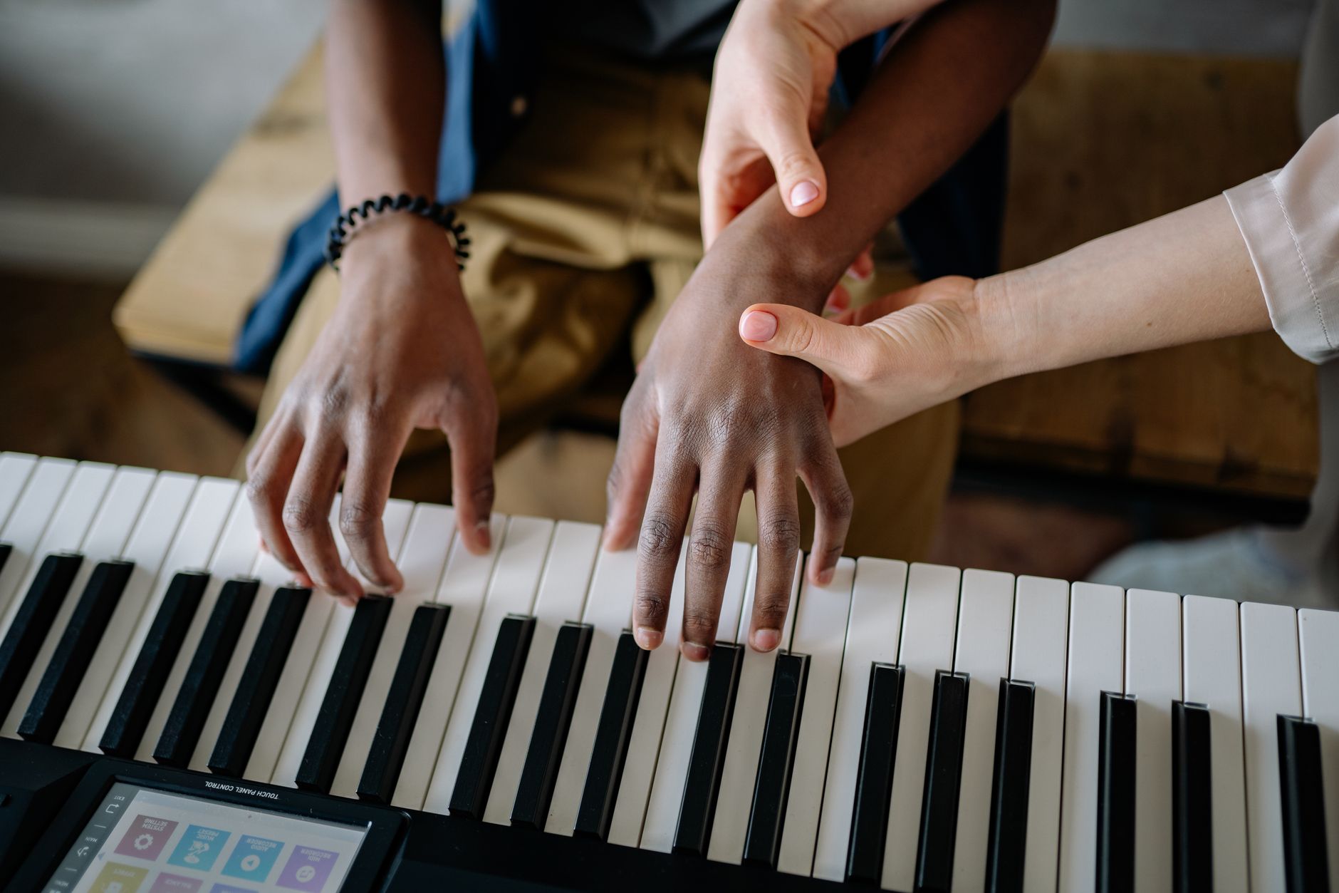 Piano teacher guiding a student at the keys