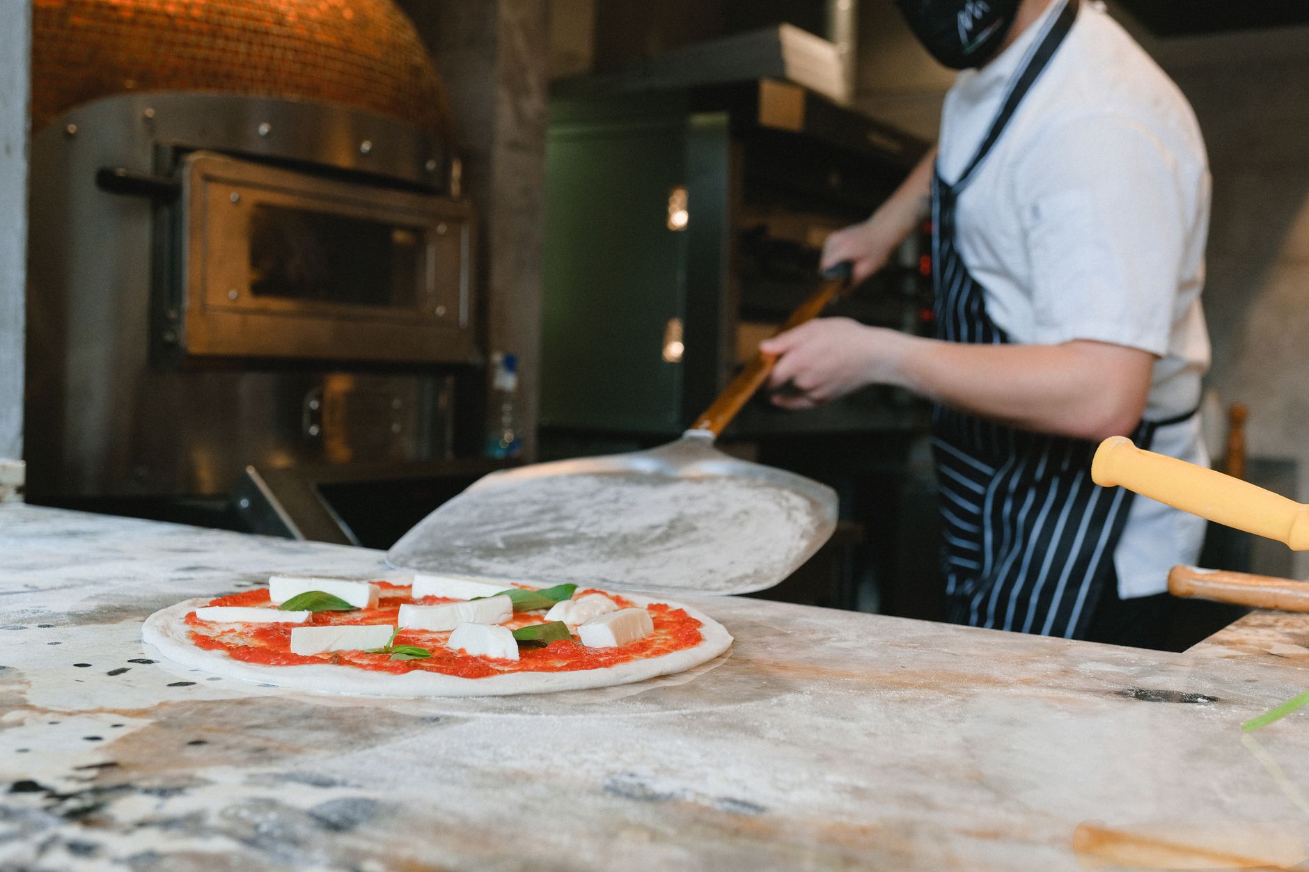 Pizza coming out of a pizzeria oven