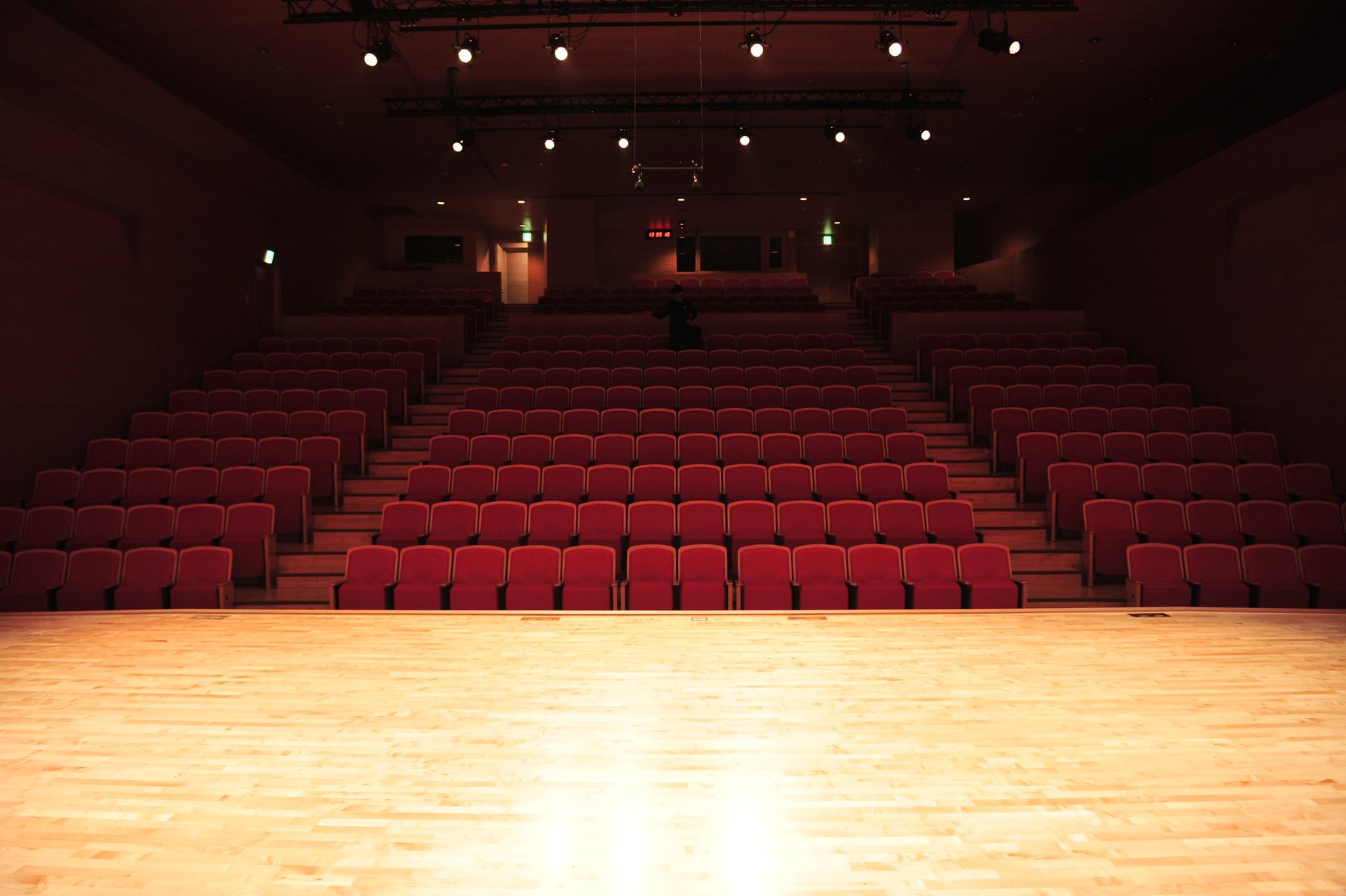 Theater interior with rows of red seats and a lit stage