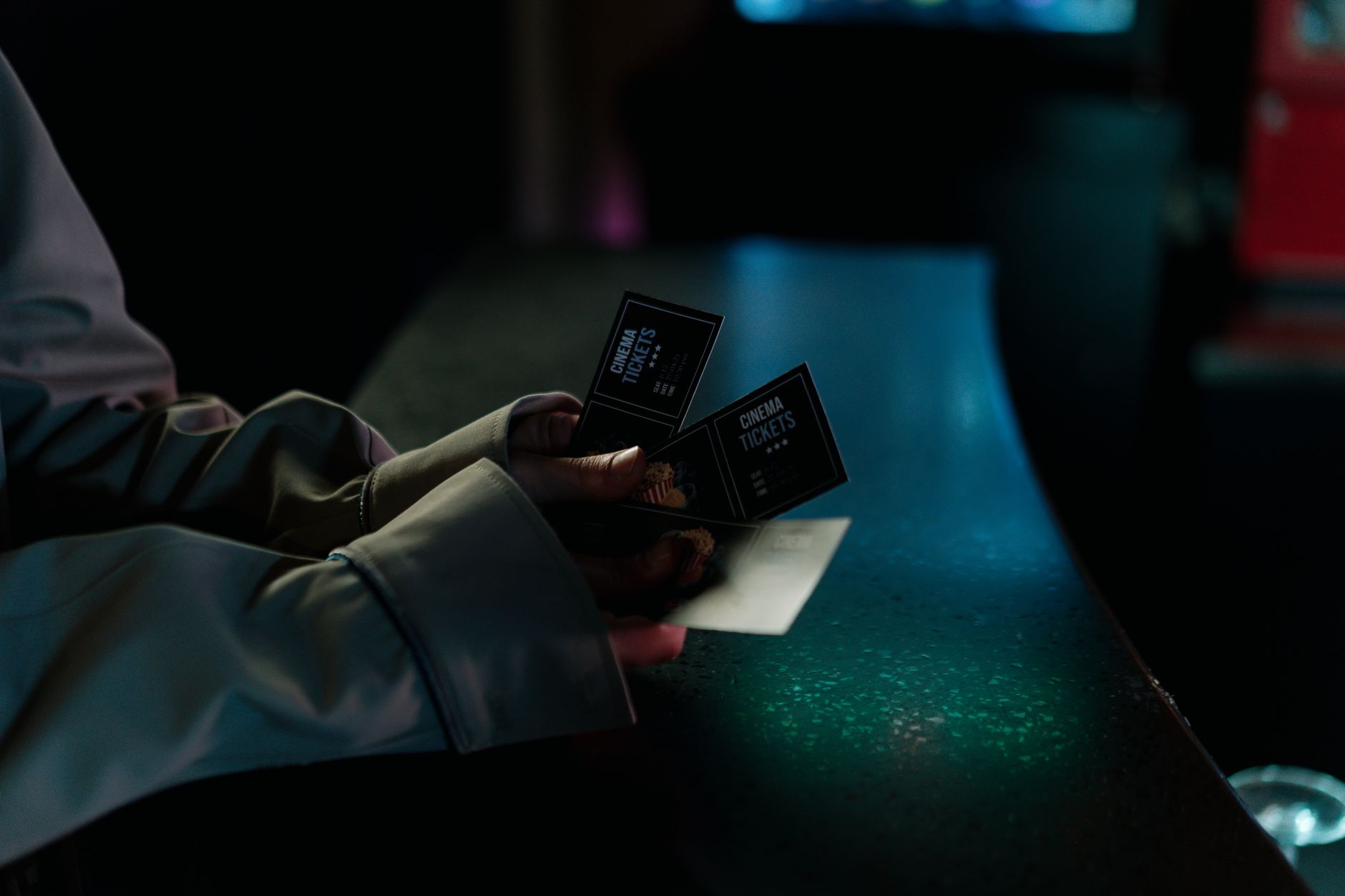 Hand holding cinema tickets at night