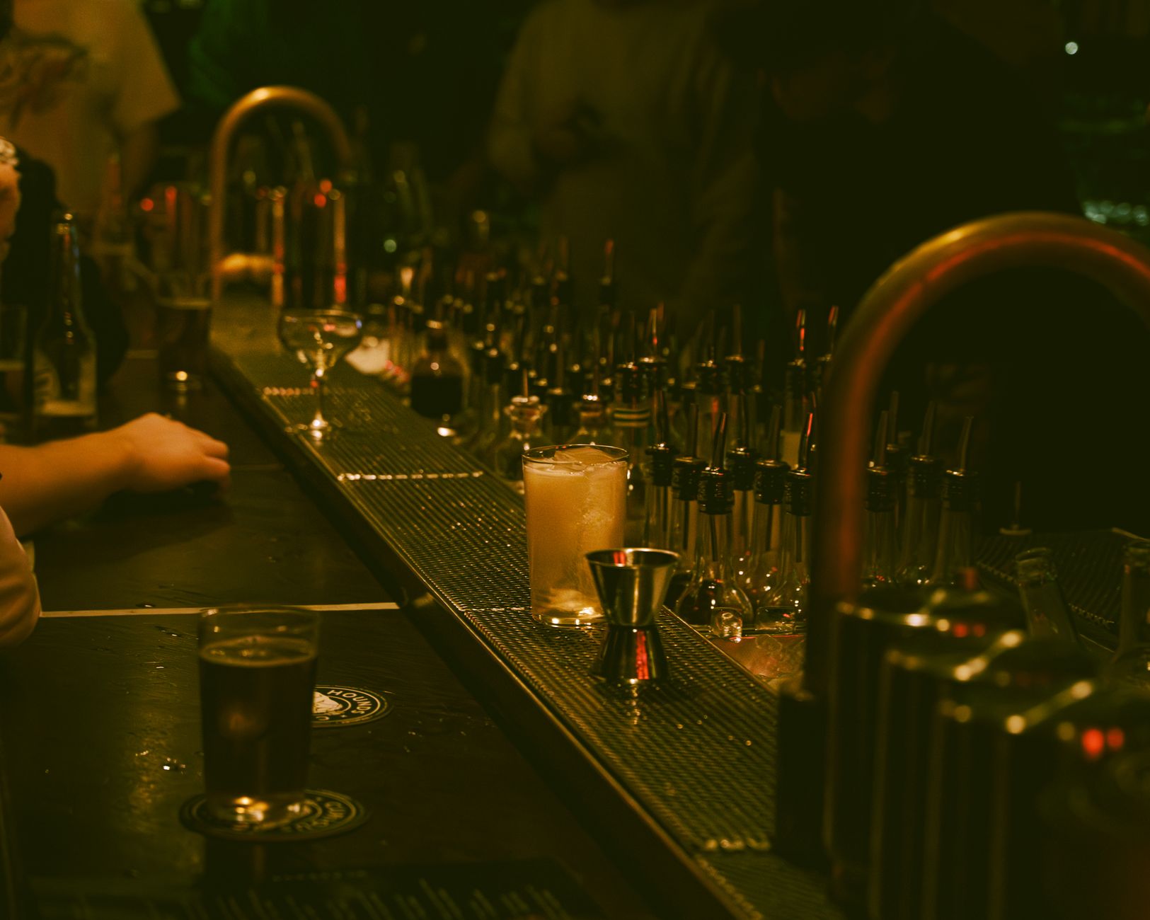 Dimly lit bar with a cocktail and bar tools