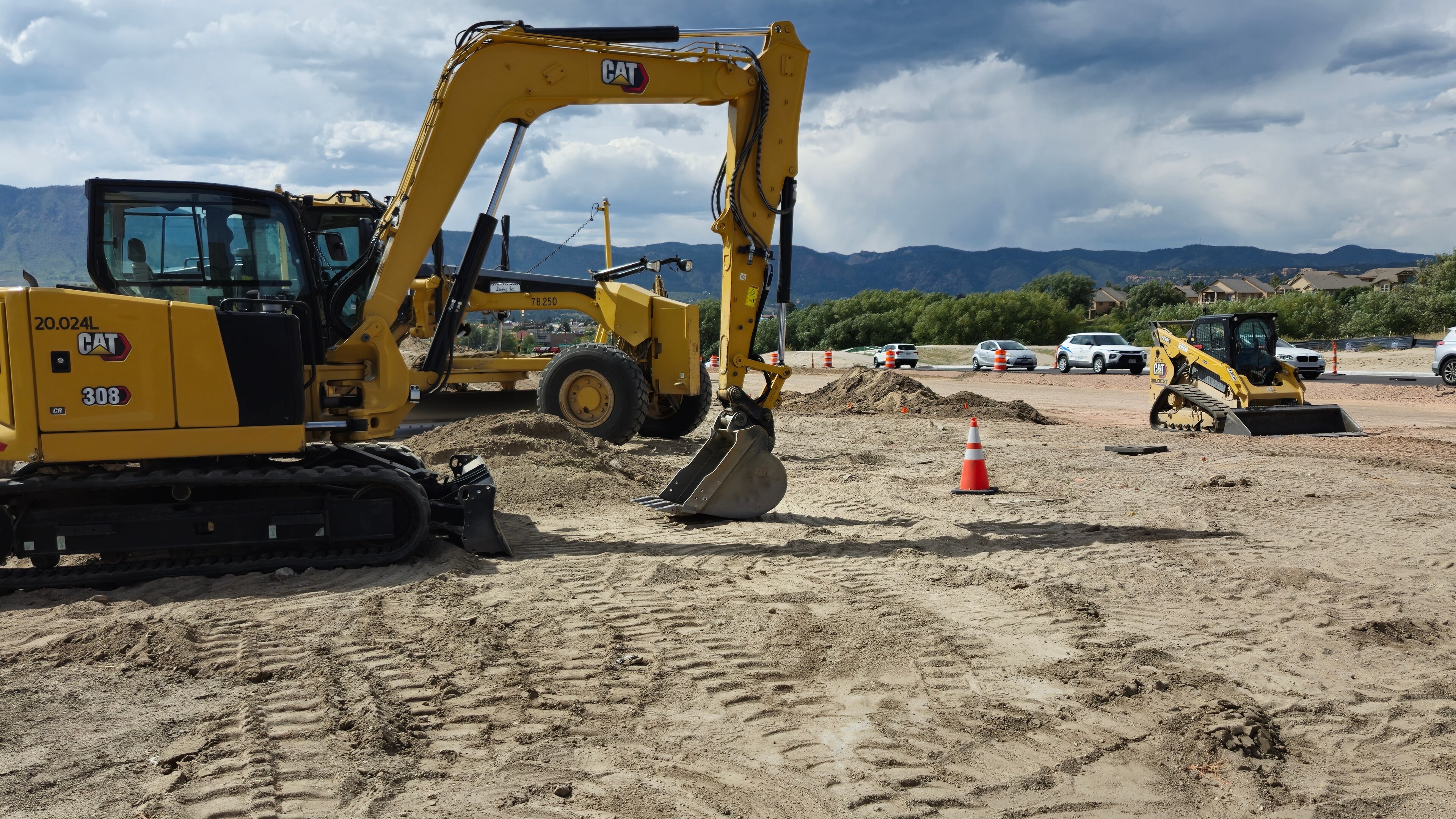 CAT construction equipment on construction site next to highway in Colorado, with mountains in background