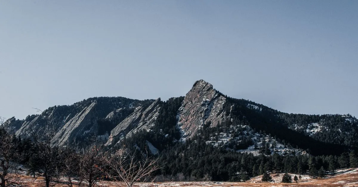 The Flatirons rise above a dry meadow at Chautauqua Park in winter.