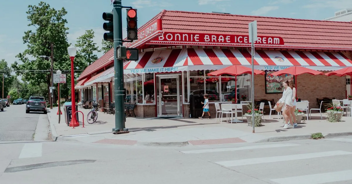 A red-striped retail corner with cafe tables, bike racks, and passersby