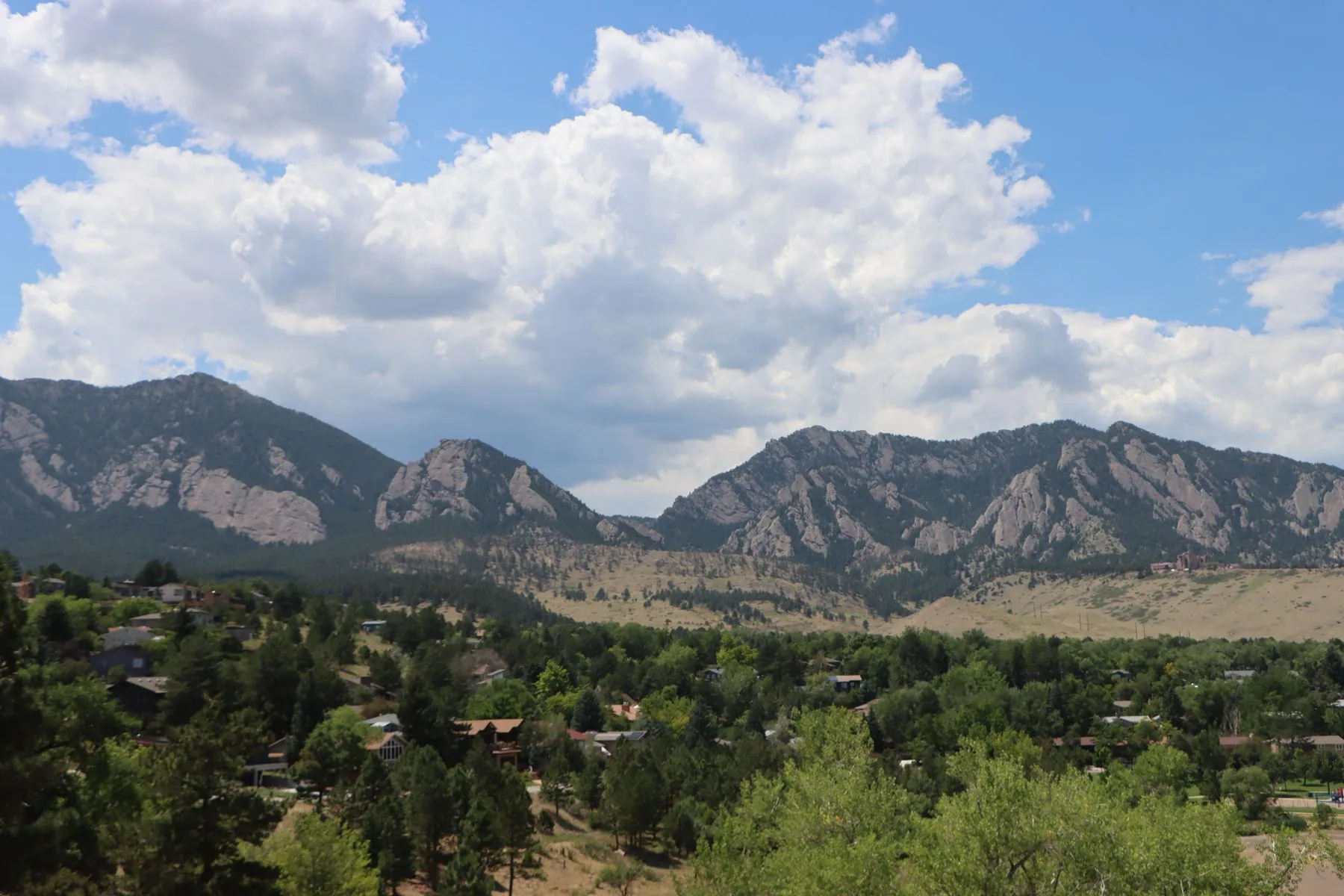Flatirons foothills rise above a tree-lined Boulder, Colorado neighborhood