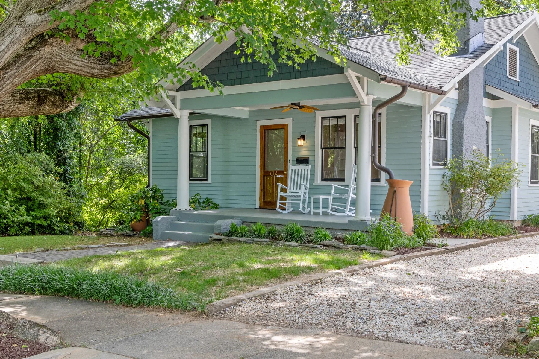 Craftsman porch with rocking chairs shaded by a large tree, a Whittier-style bungalow scene