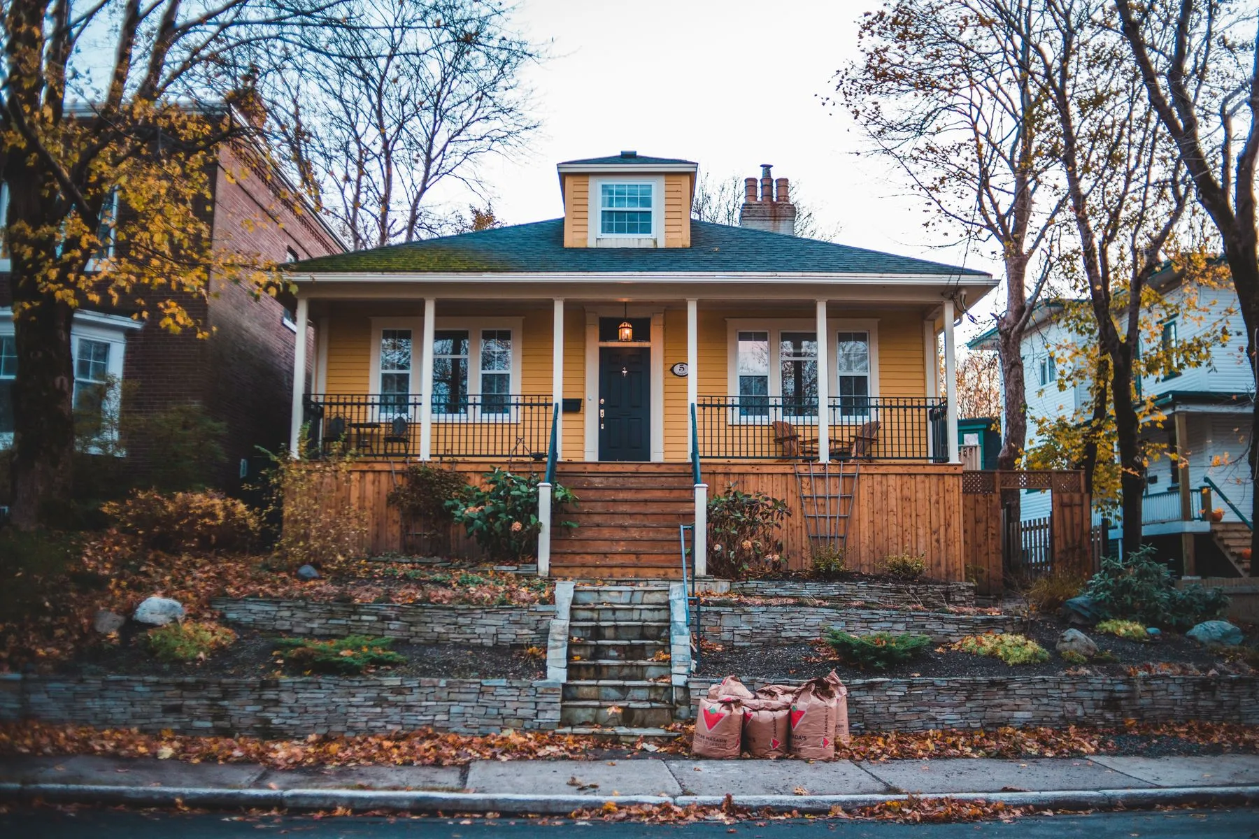 Yellow Craftsman bungalow with autumn leaves on a Boulder-style residential street